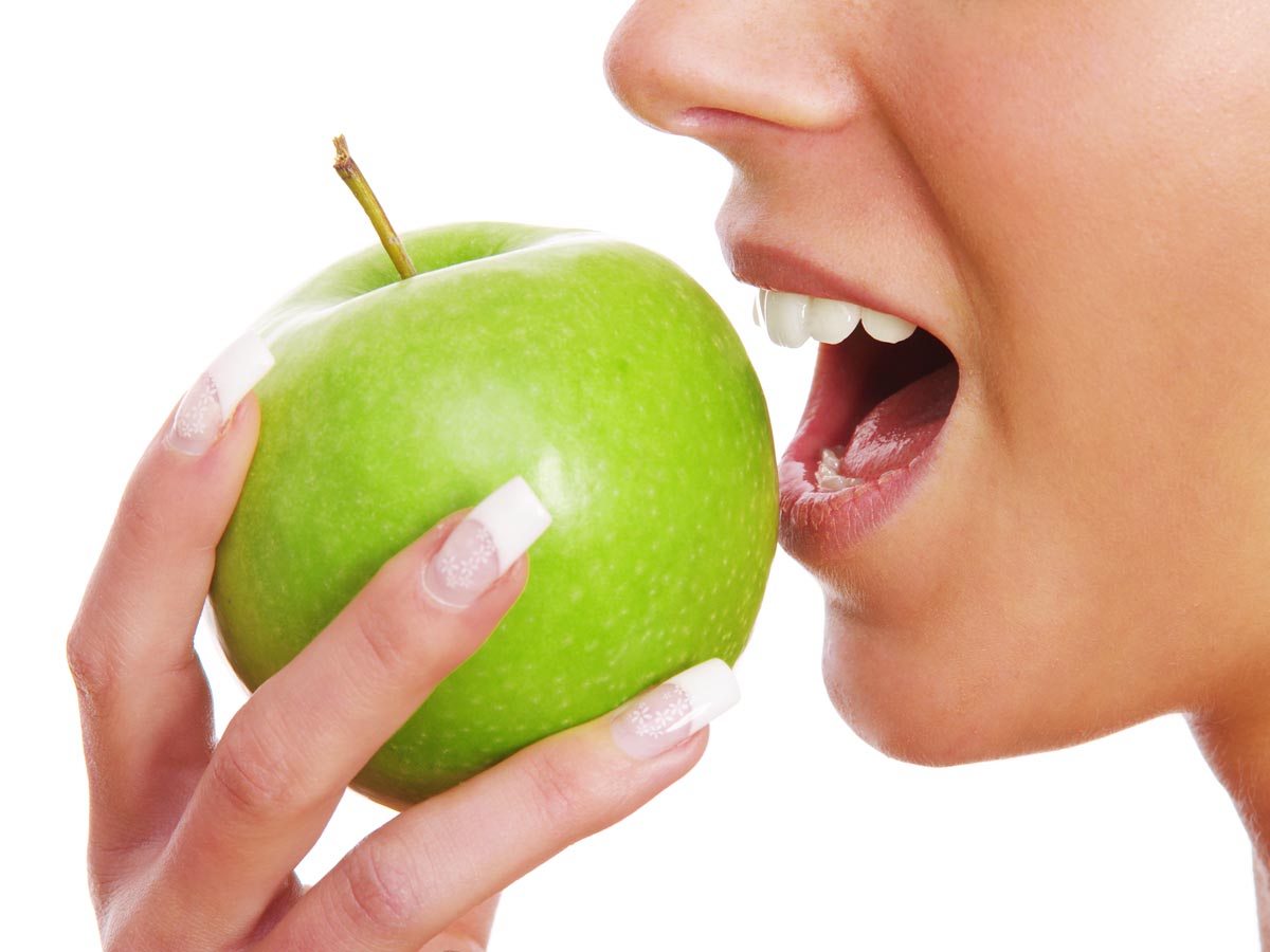 Frau beißt in einen grünen Apfel